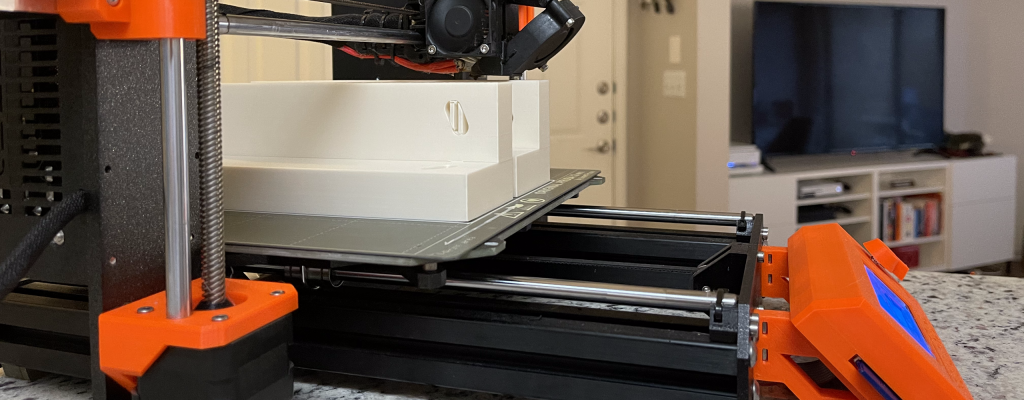 Zn original Prusa printer on a marble counter top. The printer is working on two white pieces.