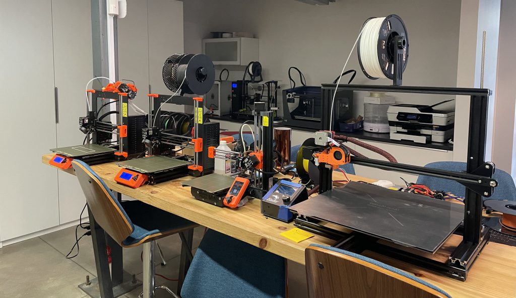Pump Studios' current office, with 7 3D printers lines up on the lunch table and the counter behind.
