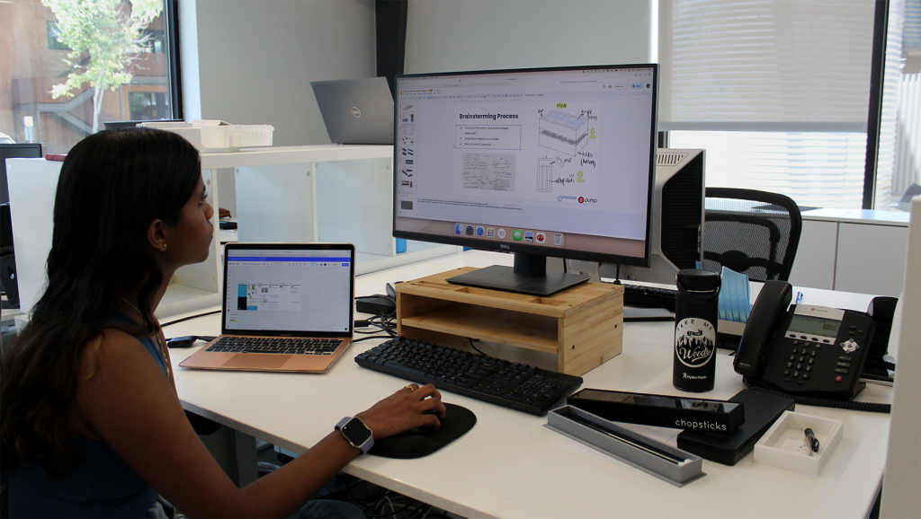 Junior Intern Amrutha working at her desk with her chop stick box siting to her right.