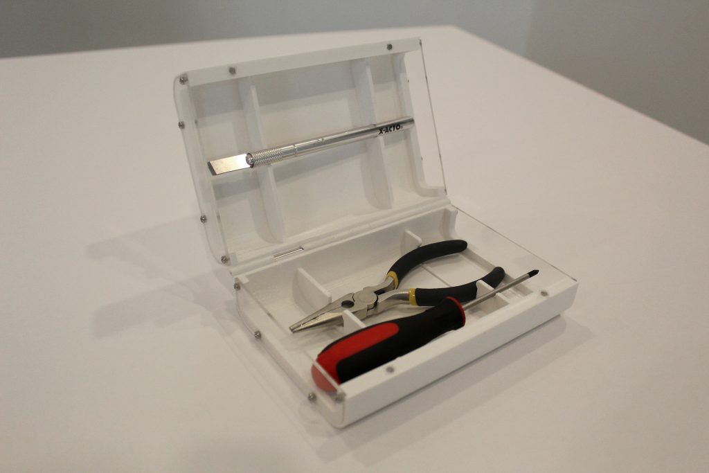 Greg's Box set up on a white surface, opened to display the internal mechanisms and tools.