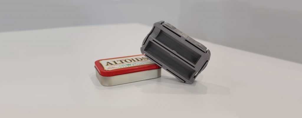 An Altoids tin with 3D printed insert angled on top.