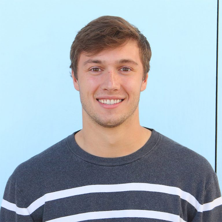 An image of Jack Moranetz smiling standing in front of a light blue wall.
