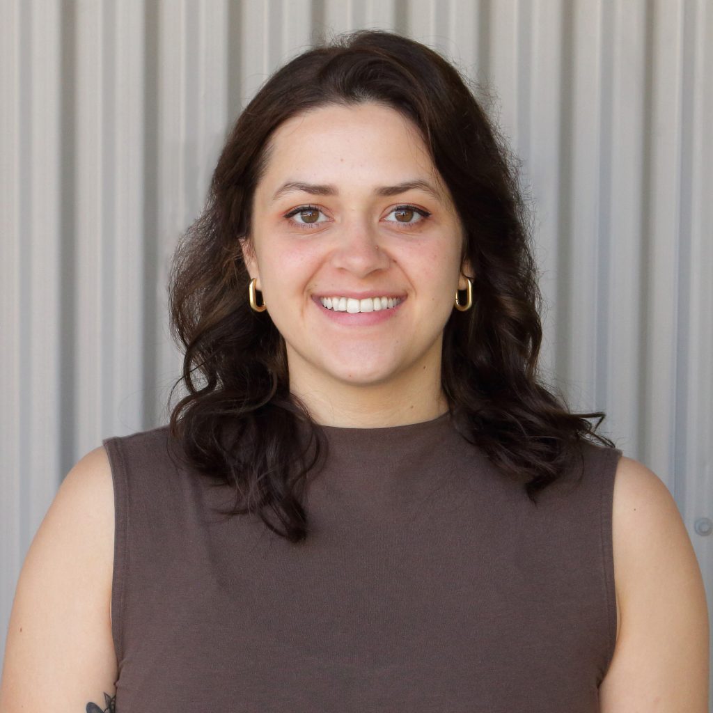 Headshot of Raiza standing in front of a metal wall.