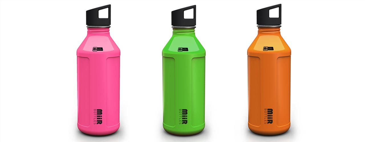 Miir metal water bottles, from left to right: pink, green, and orange. Each bottle has a little bit of writing at the top and the logo towards the base.