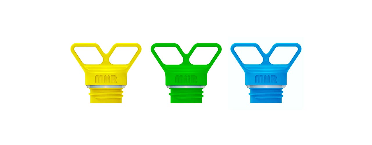 Three screw in Miir water bottle tops, one yellow, one green and one blue.